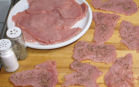 Schnitzel würzen Salzen und Pfeffern von Schnitzeln